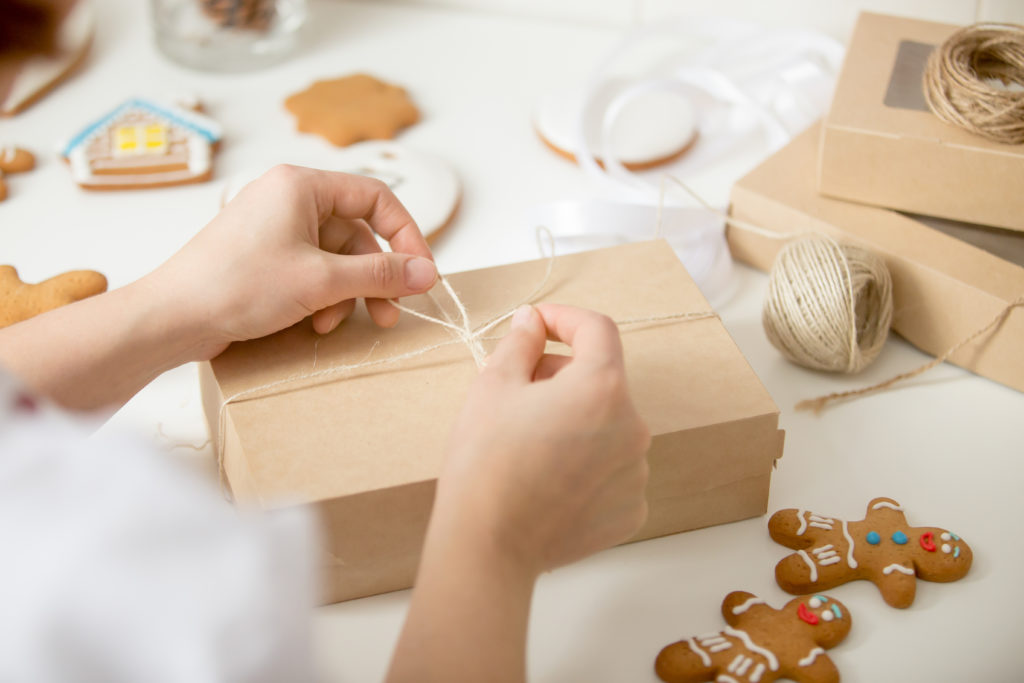close-up-confectioner-hands-wrapping-cardboard-box-1024x683