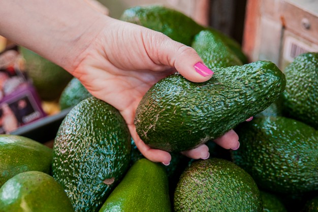 cropped-image-of-a-customer-choosing-avocados-in-the-supermarket-close-up-of-woman-hand-holding-avocado-in-market-sale-shopping-food-consumerism-and-people-concept_1391-641
