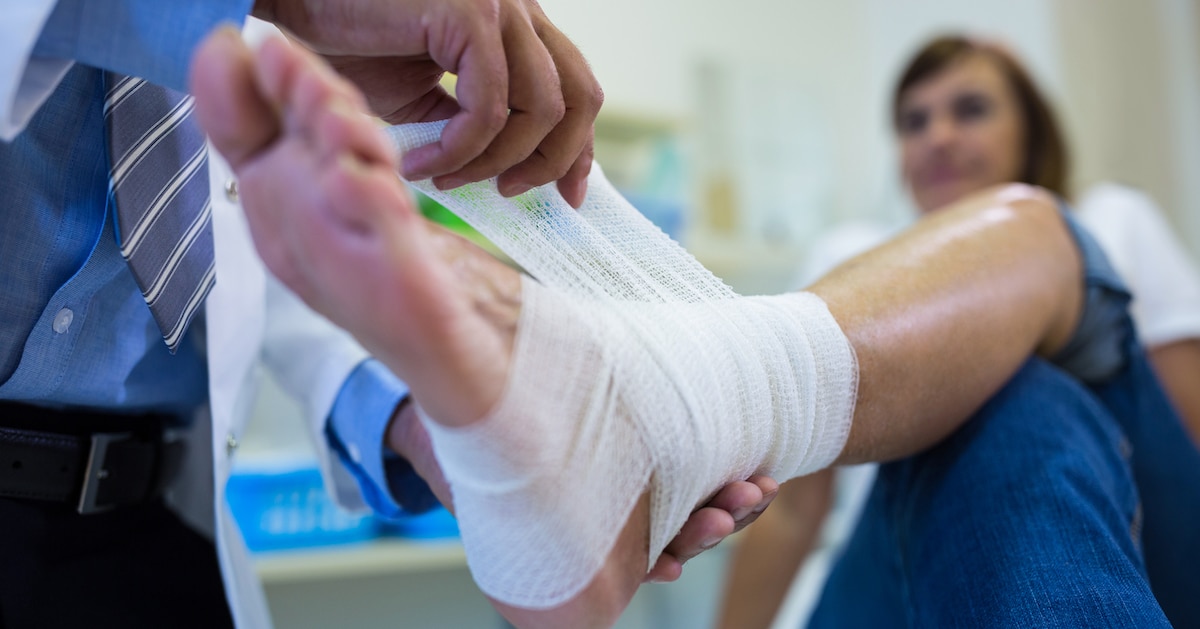male-doctor-bandaging-foot-female-patient