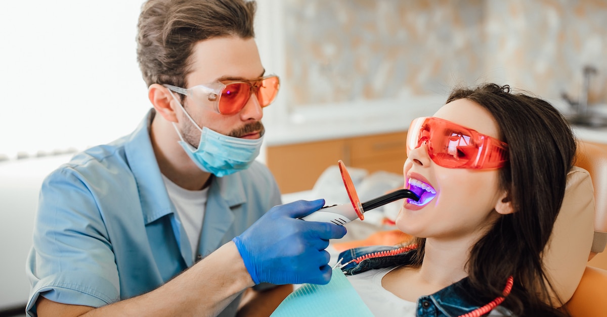 medicine-dentistry-healthcare-concept-dentist-using-dental-curing-uv-lamp-teeth-patient