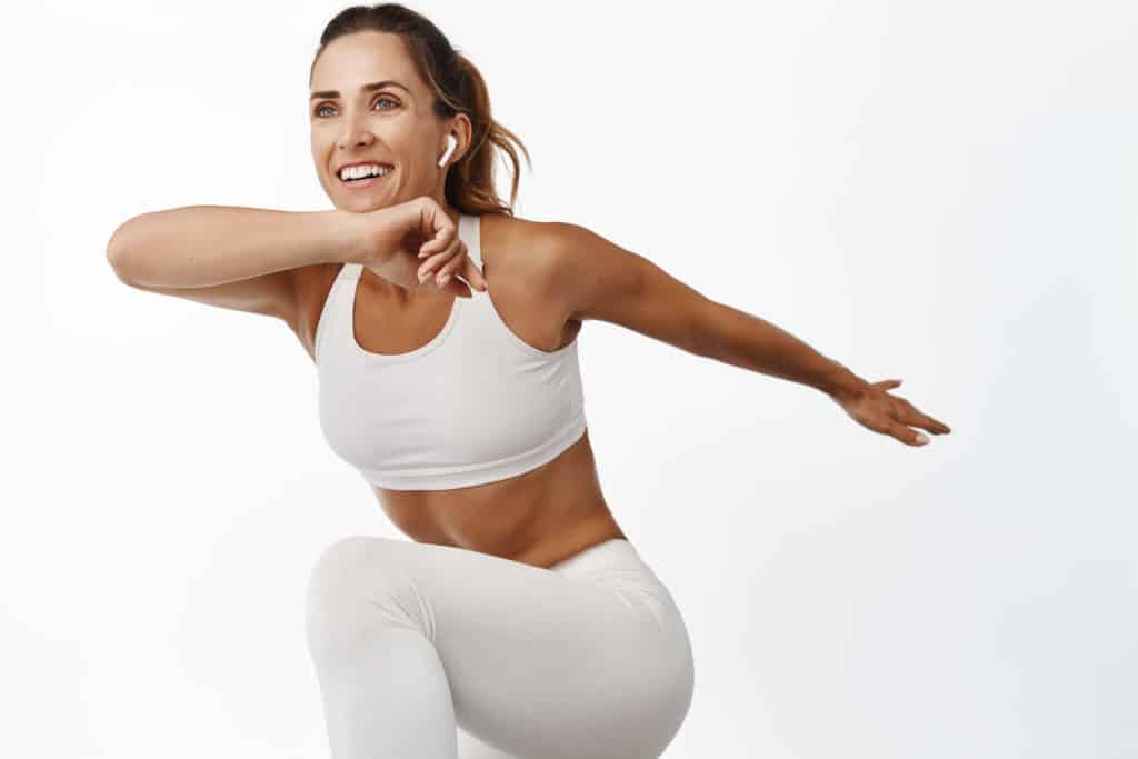 portrait-sportswoman-stretching-body-exercising-doing-fitness-leg-raise-smiling-running-standing-white-background-1024x683