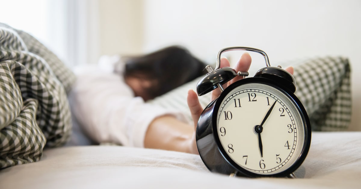 sleepy-woman-reaching-holding-alarm-clock