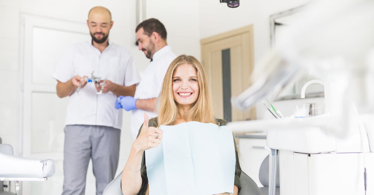 smiling-female-patient-gesturing-ok-sign-front-two-male-dentist