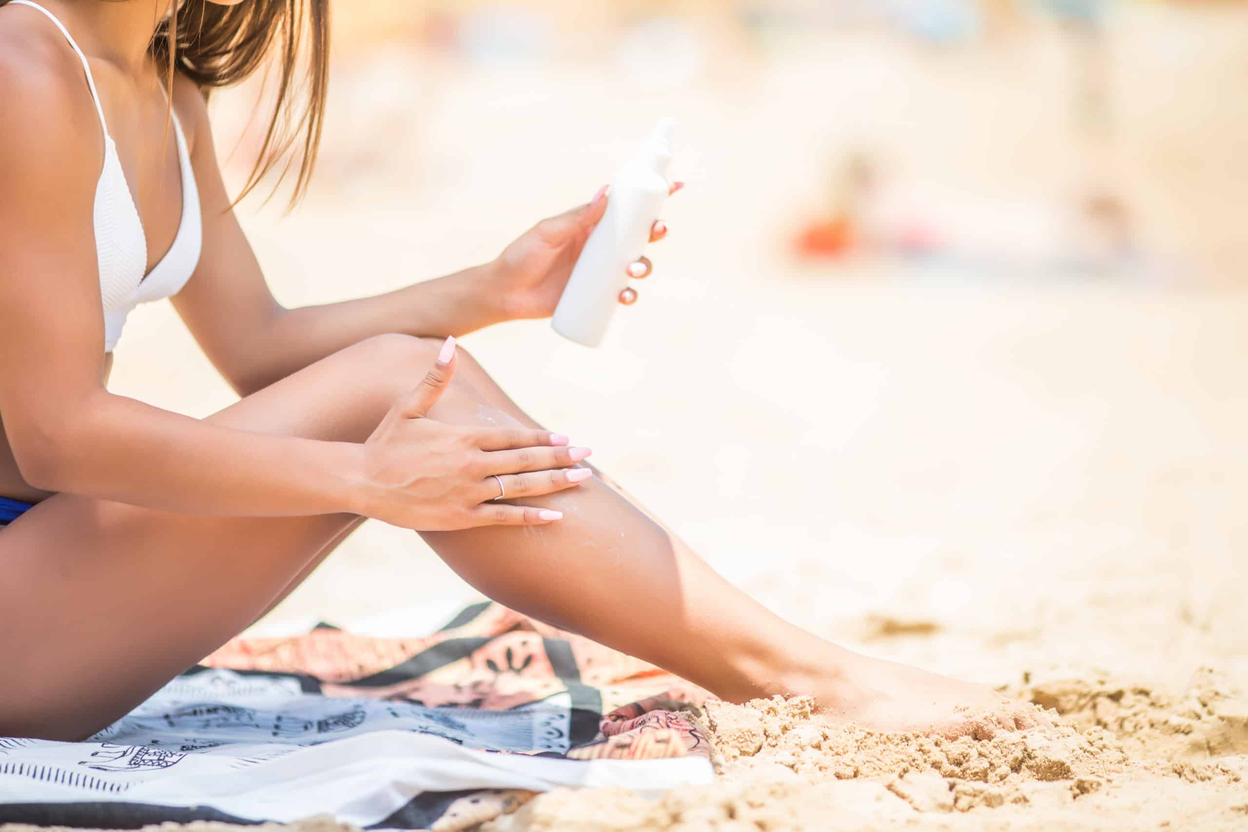 sunscreen-suntan-lotion-spray-bottle-young-woman-spraying-tanning-oil-her-leg-from-bottle-lady-is-massaging-sunscreen-lotion-while-sunbathing-beach-female-model-during-summer-vacation-scaled